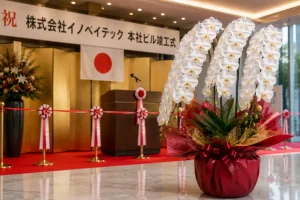 竣工祝いの胡蝶蘭|本社ビル竣工式の式典会場に届いた白の大輪+赤ラッピング